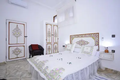 a white bedroom with a large bed with white sheets at RYAD RDATE LWALIDINE in Marrakech