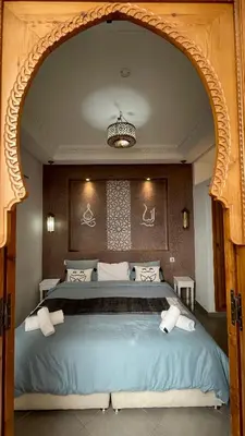 a bedroom with a large blue bed with a chandelier at Riad Al Hamama in Marrakech