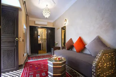 a bedroom with a bed and a table and a chandelier at Riad Mazaj in Marrakech
