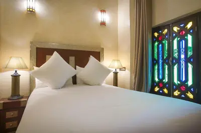 a bed with two pillows and a stained glass window at Riad Mazaj in Marrakech