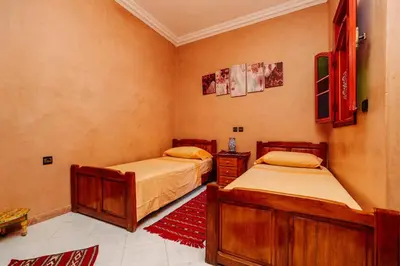 a bedroom with two beds and a red rug at Riad For S in Marrakech