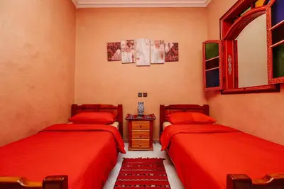 two beds in a room with red sheets at Riad For S in Marrakech