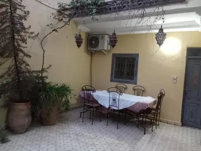 a table and chairs in a patio with a table and a tv at Riad taddert in Marrakech