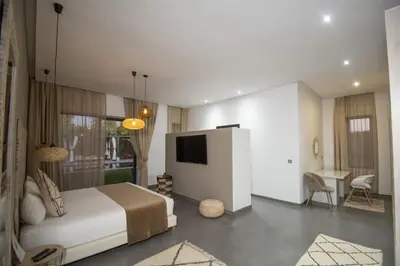 a bedroom with a bed and a television and a desk at Villa Le Clos de l'Atlas in Marrakech
