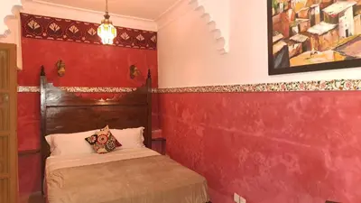 a bedroom with red walls and a bed in a room at RIAD DAR En-Nawat in Marrakech