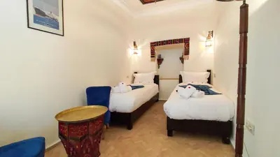 a room with two beds and a table and chairs at RIAD DAR En-Nawat in Marrakech