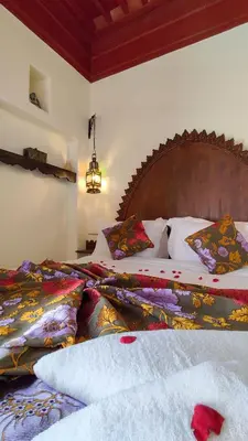 a bedroom with a large bed with a wooden headboard at RIAD DAR En-Nawat in Marrakech