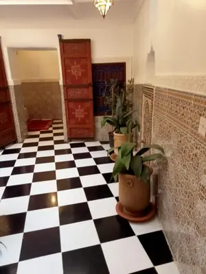 a room with a black and white checkered floor and potted plants at Riad l Ayinn in the heart of Marrakech. in Marrakech
