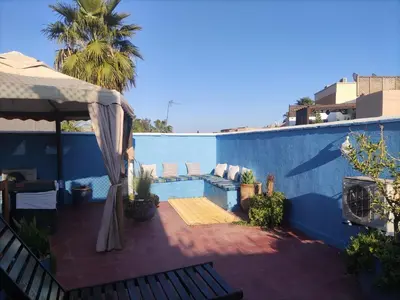a patio with a couch and a blue wall at Riad l Ayinn in the heart of Marrakech. in Marrakech