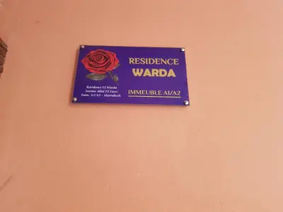 a sign on a wall with a red rose on it at Appartement warda in Marrakech