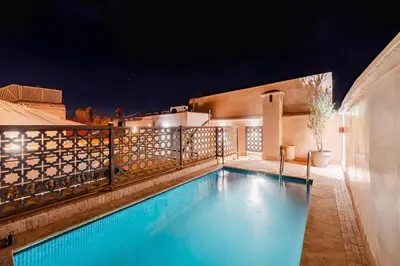 a swimming pool on the roof of a house at night at RIAD THE MILESTONE in Marrakech