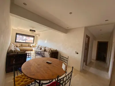 a living room with a table and a couch at Appartement cosy Gueliz avec piscine in Marrakech