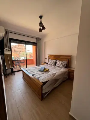 a bedroom with a large bed and a balcony at Appartement cosy Gueliz avec piscine in Marrakech