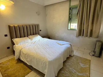 a bedroom with a large bed with white sheets and a window at Al ATLAS résidence in Marrakech