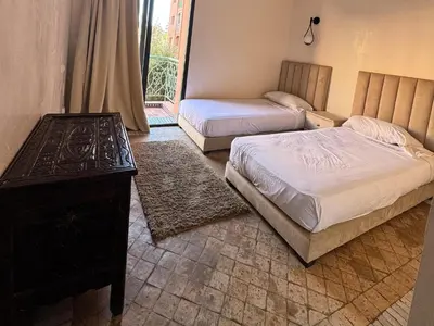 a bedroom with two beds and a table and a window at Al ATLAS résidence in Marrakech
