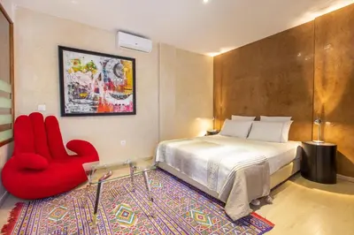 a bedroom with a bed and a red chair at Riad Princesse Des Sables- Jaccuzzi& SPA-Breakfast in Marrakech