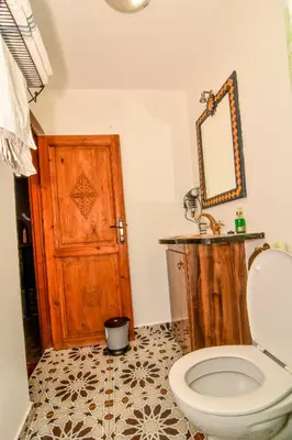 a bathroom with a toilet and a wooden door at Riad ouhmidi in Marrakech