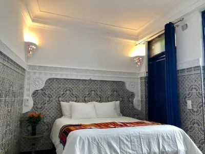 a bedroom with a white bed with a blue curtain at Riad Imndi in Marrakech