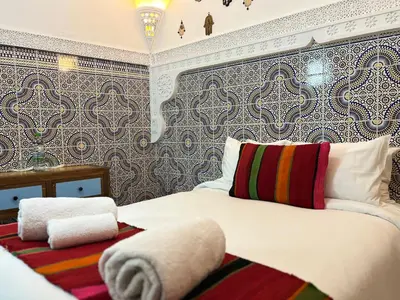 a bedroom with a large white bed with a patterned wall at Riad Imndi in Marrakech