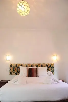 a bedroom with a white bed with a floral headboard at Riad Imndi in Marrakech