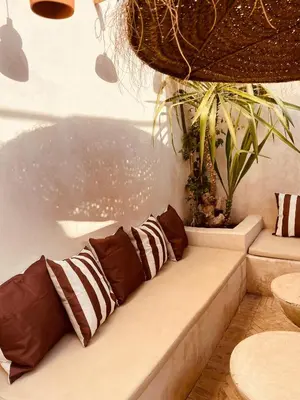 a couch with pillows sitting on it next to a plant at Riad Nekhla in Marrakech
