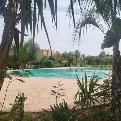 a swimming pool with people in the water at Atlas golf rossort in Marrakech