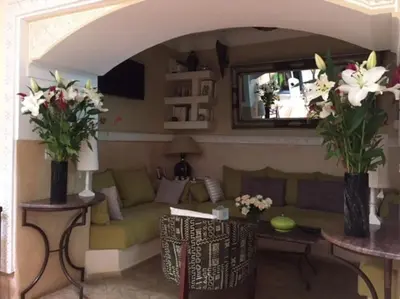 a living room with a green couch and flowers in vases at Dar Nassima in Marrakech