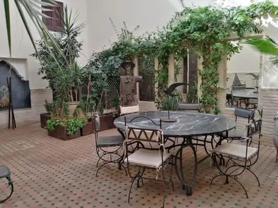 a table and chairs in a courtyard with plants at Dar Nassima in Marrakech