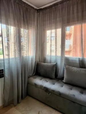 a couch sitting in front of two windows with curtains at Appartement en plein centre ville entièrement équipé in Marrakech