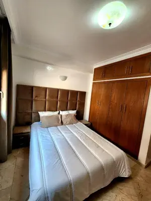 a bedroom with a large bed with a wooden headboard at Appartement en plein centre ville entièrement équipé in Marrakech