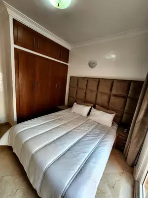 a bedroom with a large bed with a wooden headboard at Appartement en plein centre ville entièrement équipé in Marrakech