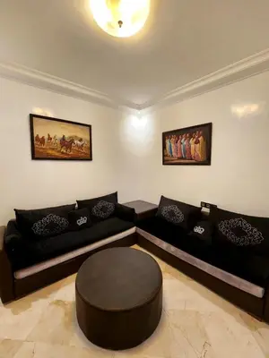 a living room with a black couch and a stool at Appartement en plein centre ville entièrement équipé in Marrakech