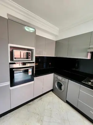 a white kitchen with a washer and a microwave at Appartement en plein centre ville entièrement équipé in Marrakech