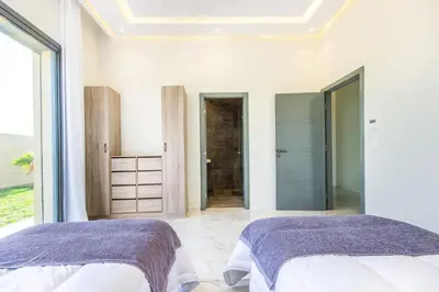 two beds in a white room with a window at Villa California, sans vis à vis, piscine Chauffée, Spa, in Marrakech