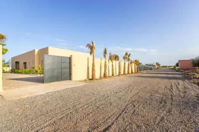 a road with palm trees in front of a building at Villa California, sans vis à vis, piscine Chauffée, Spa, in Marrakech