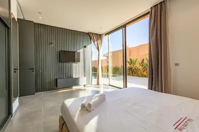a bedroom with a white bed and a television at Villa Perle Rouge, Piscine , Cuisinière, Billard, playStation5 in Marrakech