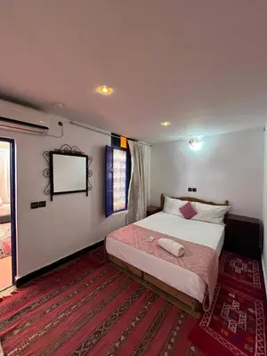 a bedroom with a bed and a tv on the wall at Riad La Rose Des Sables in Marrakech
