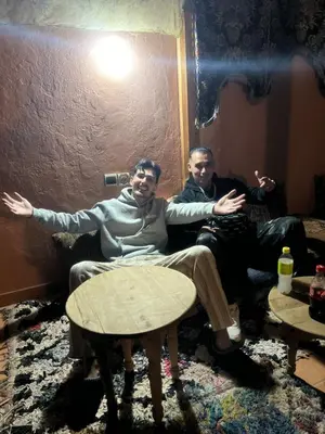 two men sitting in a room with their arms out at Riad La Rose Des Sables in Marrakech