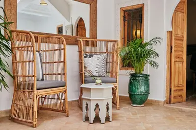 two chairs and a table in a room with a plant at Ryad Selyen in Marrakech