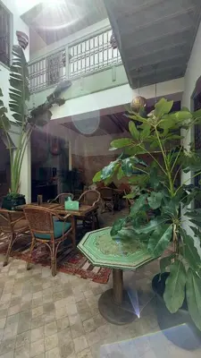 a living room with tables and chairs and plants at Riad Lalla Mimouna in Marrakech