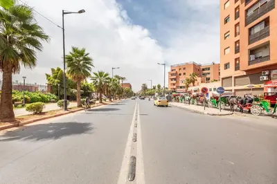 a street with palm trees and a yellow car driving down the street at L'Atelier N°12, Loft, Terrasse in Marrakech