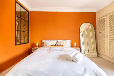 a bedroom with a large white bed with orange walls at L'Atelier N°12, Loft, Terrasse in Marrakech