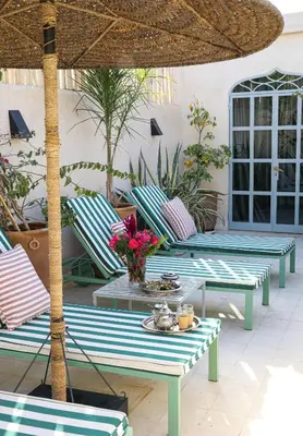 a patio with blue and white chairs and an umbrella at Riad Amour in Marrakech