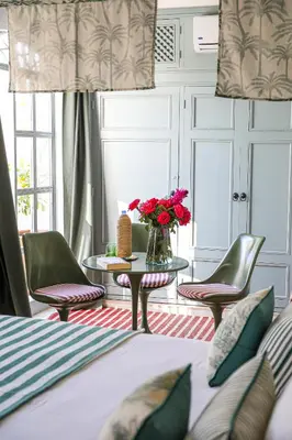 a bedroom with a bed and chairs and a table with flowers at Riad Amour in Marrakech