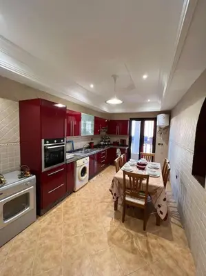 a kitchen with red cabinets and a table with chairs at Superbe appartement avec parking gratuit in Marrakech