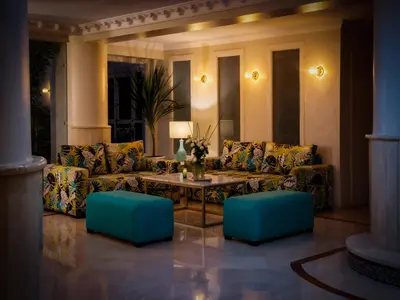 a living room with couches and a table and blue stools at Hotel Safia in Marrakech