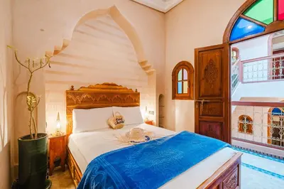 a bedroom with a large bed with a blue blanket at Riad Cozy Marrakech, Shared Pool with 3 Rooms in Marrakech
