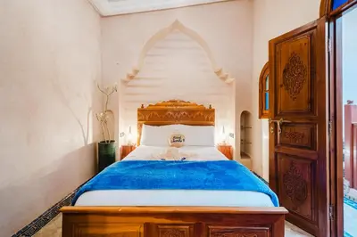a bedroom with a large bed with a wooden headboard at Riad Cozy Marrakech, Shared Pool with 3 Rooms in Marrakech