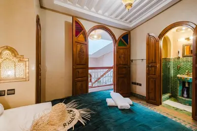 a room with a bed and a bathroom with a window at Riad Cozy Marrakech, Shared Pool with 3 Rooms in Marrakech