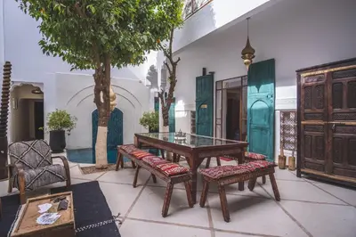 a room with a table and benches and a tree at Riad Villa Berna under Swiss Management in Marrakech